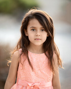 Outdoor portrtait of little girl with long hair looking at camera, childhood memories and summer holidays concept