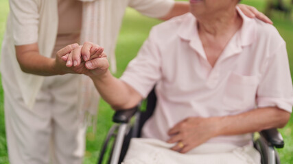 Asian senior couple support healthcare holding hands wheelchair park garden elderly care retirement...