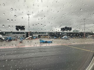 View on airport through plane window with raindrops