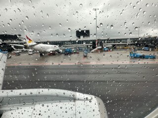 View on airport through plane window with raindrops