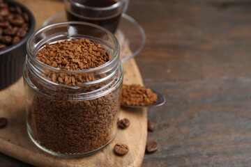Instant coffee in glass jar, hot drink and beans on wooden table, closeup. Space for text
