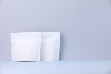 Two zipper stand-up pouches on light grey background. Mockup for design