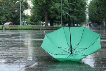 Green umbrella under heavy rain outdoors, space for text