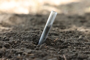 Test tube with soil sample outdoors, closeup. Space for text