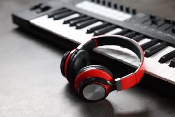 MIDI keyboard and headphones on grey table, closeup. Space for text