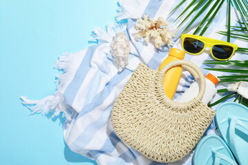 Beach accessories, sea shells and palm leaves on light blue background, flat lay