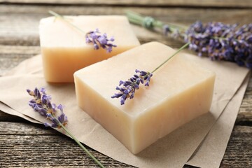 Aromatic soap bars and lavender flowers on wooden table, closeup