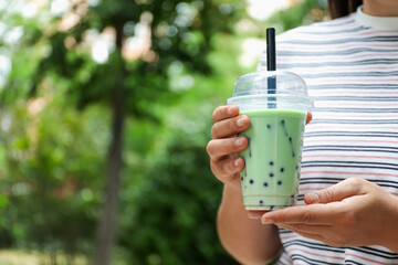 Woman with tasty milk bubble tea in plastic cup outdoors, closeup. Space for text