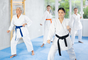 Experienced skilled young female karate sensei wearing white kimono adorned with black belt to...