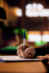 Mature college student completing class notes on printed papers, writing important information in a...