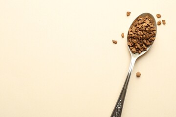 Spoon with instant coffee on beige background, top view. Space for text