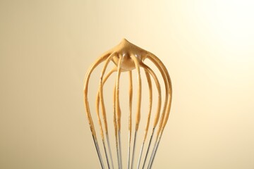 Making delicious dalgona coffee. Whisk with cream on beige background, closeup