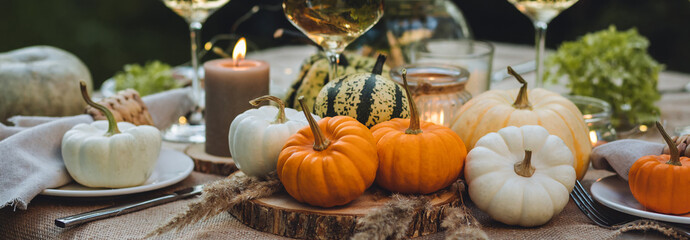 Banner. Cozy fall table decoration for Thanksgiving family dinner, romantic autumn wedding outdoors with small pumpkins, candles. White wine. Countryside style, cottage core, beautiful elegant setting