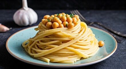 Towering spaghetti topped with chickpeas and garnish, on light blue plate against dark backdrop.
