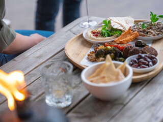 Mediterranean appetizer spread with hummus falafel vegetables and flatbread accompanied by wine glass and candlelight