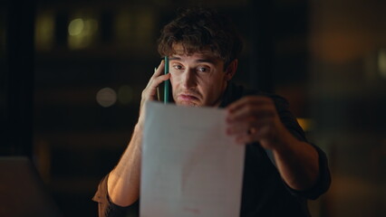 Positive consultant talking cellphone looking laptop at night office closeup.