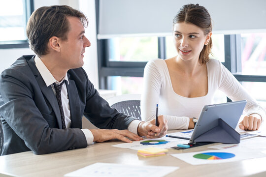Diverse Team Working Together in Modern Co-Working Space. Casual meeting of smiling diverse business team analyzing financial data. Multiethnic business people working together in the office.
