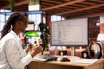 Cheerful engineer in home office celebrating after successfully executing programming code, looking...