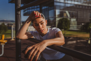 tired woman take a brake in the outdoor gym rest on the bars