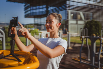 caucasian sportswear at outdoor gym filming herself on camera