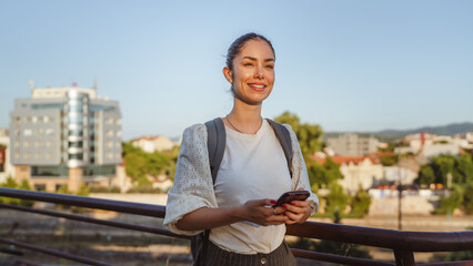 portrait of smiling woman use mobile phone while walking outdoor