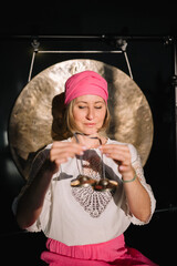 Close-up view of woman using singing bowl in sound healing therapy indoors. 
