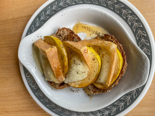 baked melted goat cheese and pear on rustic bread plate on wood table, top down view