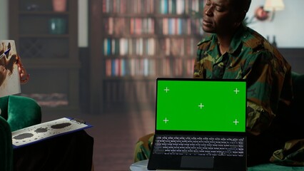 Military trooper studies Rorschach inkblot illustration next to green screen in therapy with psychologist, addressing PTSD and trauma recovery problems. Psychological support. Camera B.