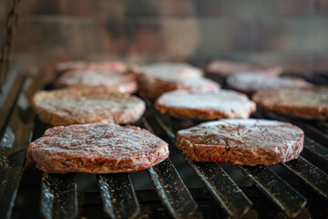Perfectly portioned beef burgers beginning to cook on the grate.
