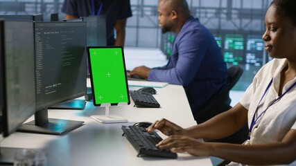 Admin using isolated screen tablet, working in server farm to optimize it for data processing...
