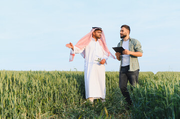 Arab businessman and farmer discussing in wheat field
