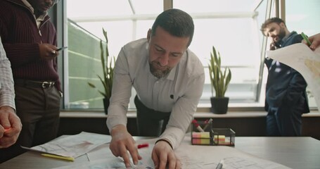 A diverse team of business professionals collaborates on a project in a modern office, reviewing blueprints and discussing strategies. Teamwork, innovation, and expertise drive their success. - Powered by Adobe