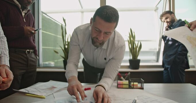 A diverse team of business professionals collaborates on a project in a modern office, reviewing blueprints and discussing strategies. Teamwork, innovation, and expertise drive their success.