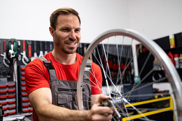Professional caucasian serviceman repairing and servicing bicycle in workshop.