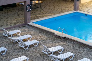 Empty outdoor swimming pool area with sunbeds and a recreation patio, ideal for a tranquil summer...