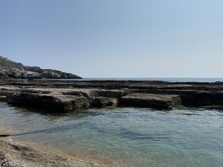 Dark layered rock slabs on the shore of Koru Beach in Alanya, Turkey. Unique natural patterns, coastal landscape, scenic geology