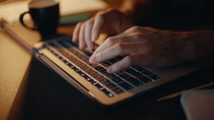 Programmer hands typing code at laptop keyboard at night apartment closeup. 