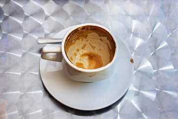 Empty espresso cup with crema stains on saucer at cafe table.  Top view. Selective focus
