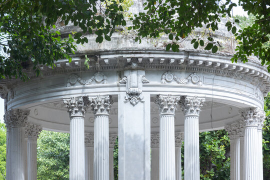 Detailed view of a neoclassical stone tempietto with ornate Corinthian columns in a garden