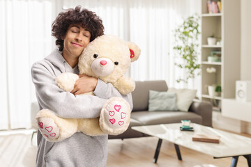 Smiling young man hugging a teddy bear
