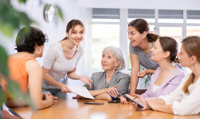 Positive interested young woman participating in volunteer work discussing new projects or events...