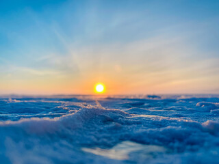 Macro closeup of snow and ice on a winter landscape at sunset with glowing sky