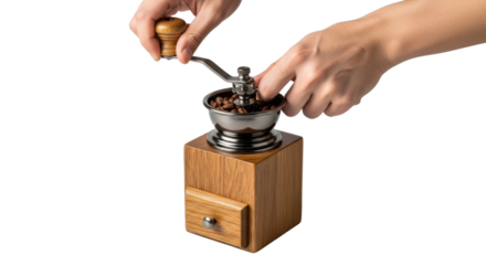 A person hands turn the crank of a classic wooden coffee grinder, processing whole beans for a fresh cup. Ideal for illustrating morning routines or beverage preparation.