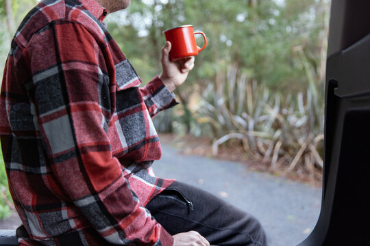 Man enjoying hot beverage with red shirt and red cup on road trip stop