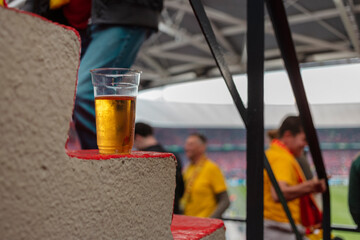 Glass of beer on stadium concrete steps with sports fans in background during live sporting event © Victor