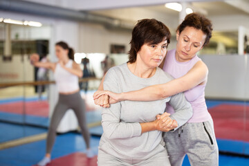 Emotional woman trying to escape from back grip and delivering elbow strike to midsection to female...
