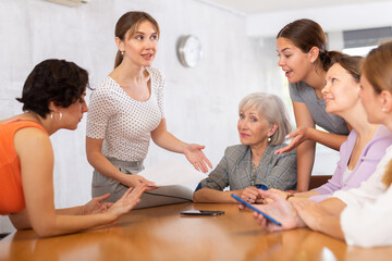 during teamwork, young woman student sitting on table near friends and actively promotes her...