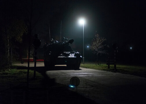 PzH 2000NL artillery piece positioned under street lighting during nighttime operations creating dramatic illuminated scene