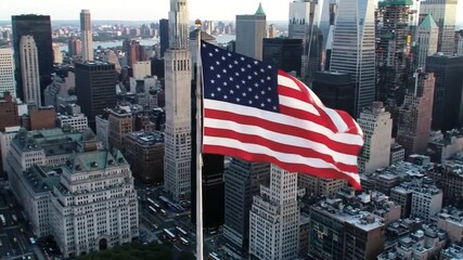 Aerial view of the american flag waving over a dense cityscape with tall buildings - Powered by Adobe