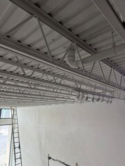 Industrial building interior showcasing exposed steel truss ceiling system with complex framework...